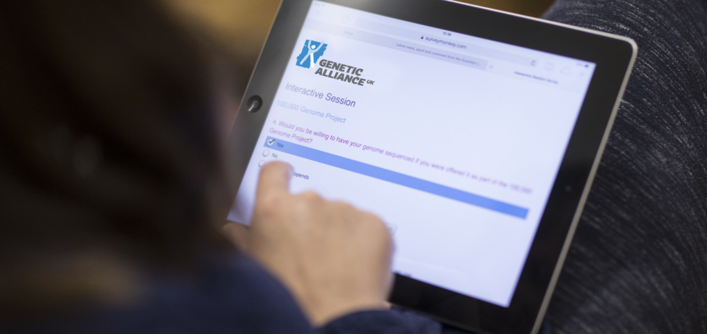 A person using a digital tablet that has a Genetic Alliance UK newsletter sign up form on it