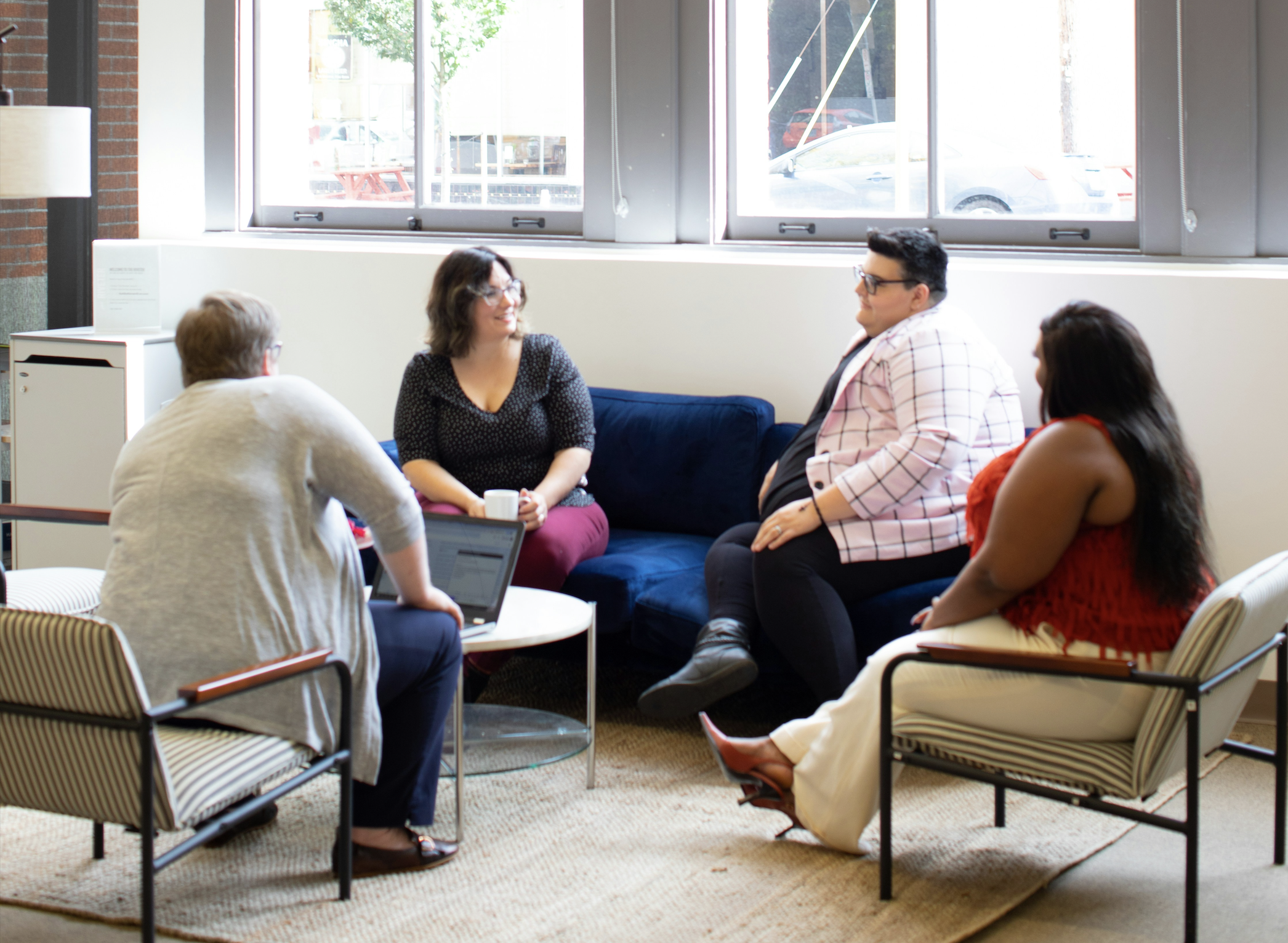 A group of 4 woman say around in a supportive group setting