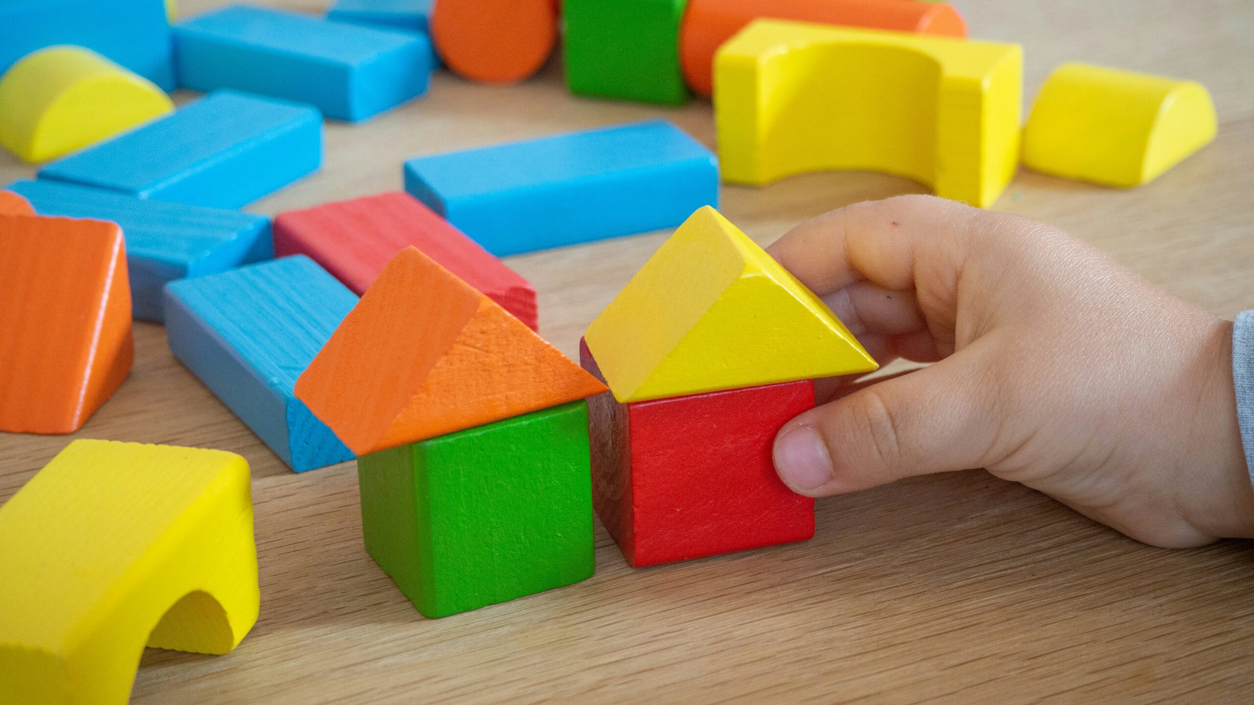 Photo by Michał Bożek on Unsplash. A child's hands playing with colourful building blocks
