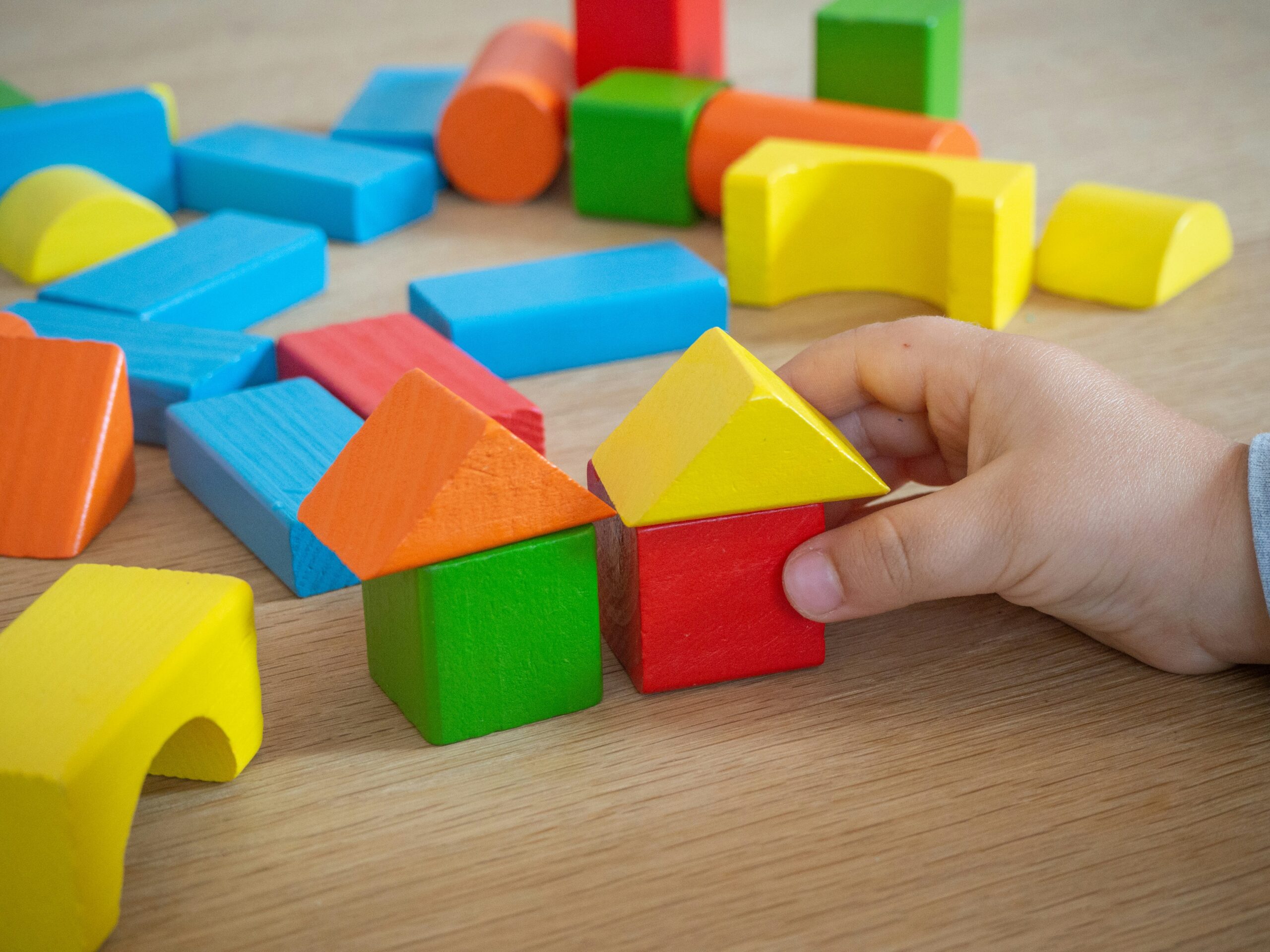Photo by Michał Bożek on Unsplash. A child's hands playing with colourful building blocks